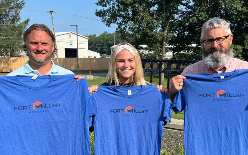 fort miller precast employees holding up shirts with the new logo