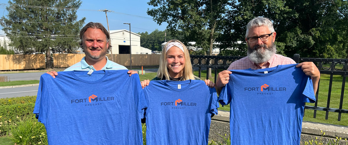 fort miller precast employees holding up shirts with the new logo